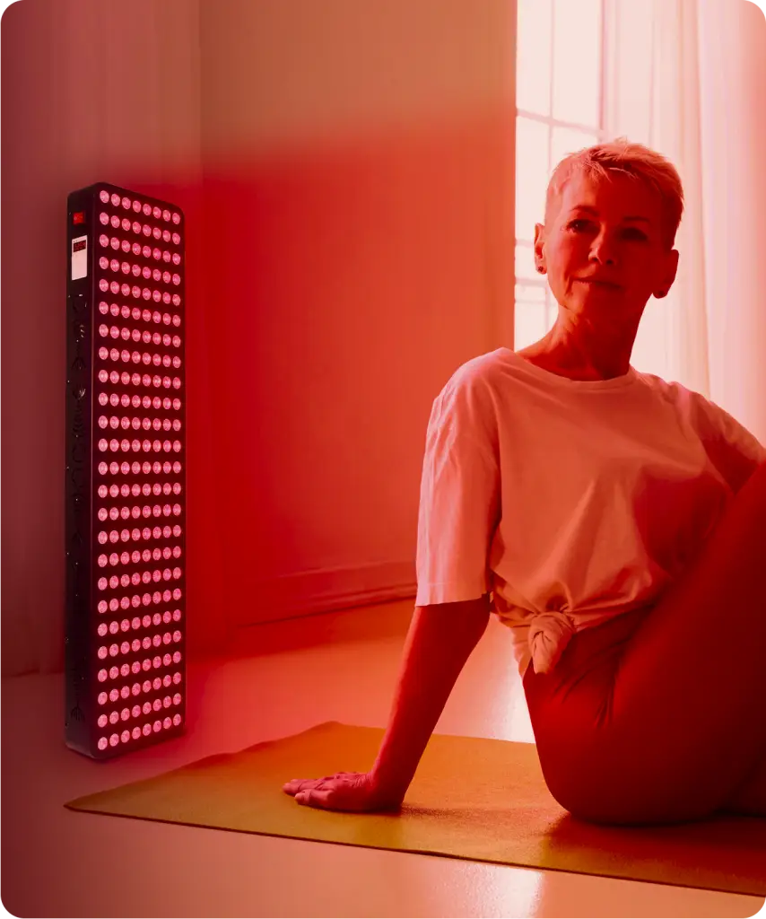 Woman sitting in front of a red light therapy panel